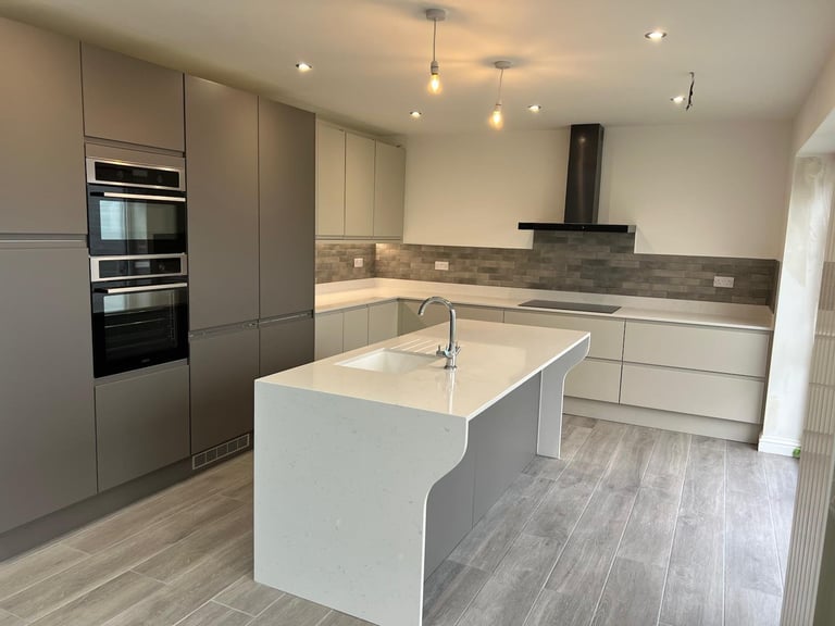 Modern kitchen with white island, gray cabinetry, stainless steel appliances, and gray tile backsplash