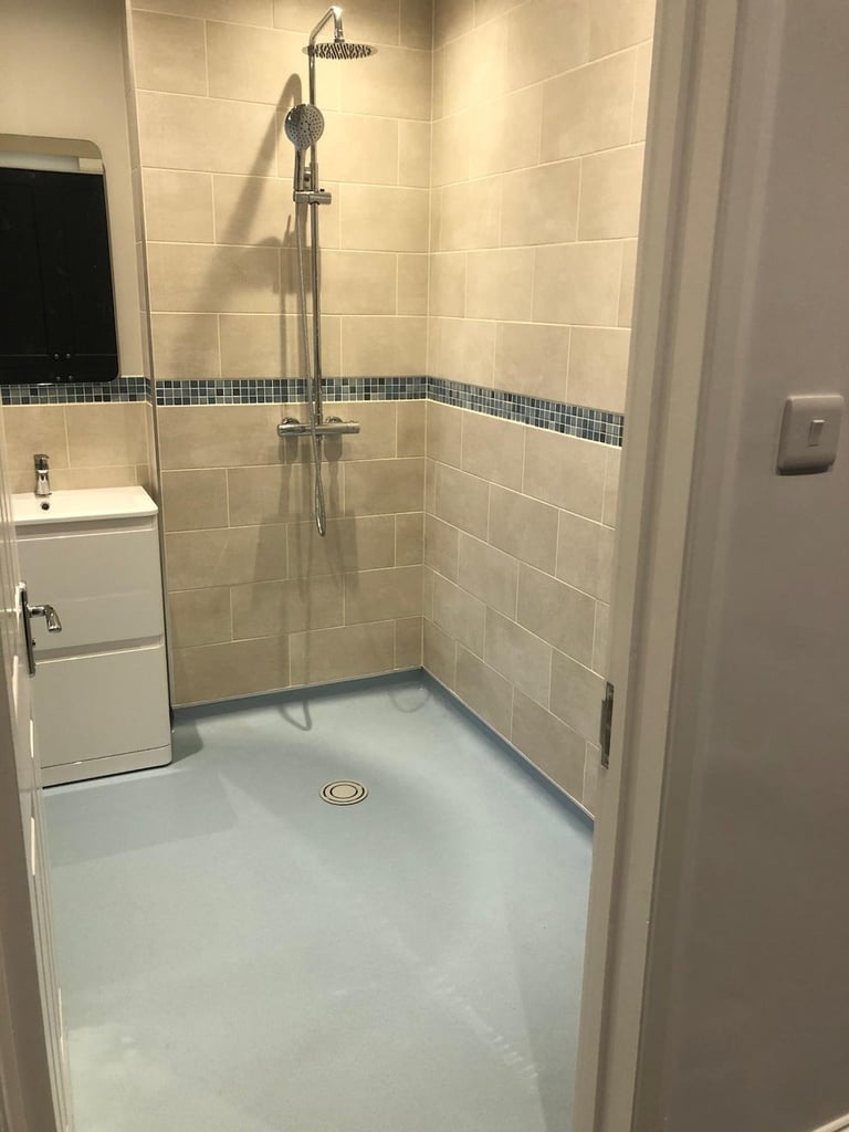 Modern tile shower enclosure with rainfall showerhead, white subway tiles, blue accent stripe, and white base floor