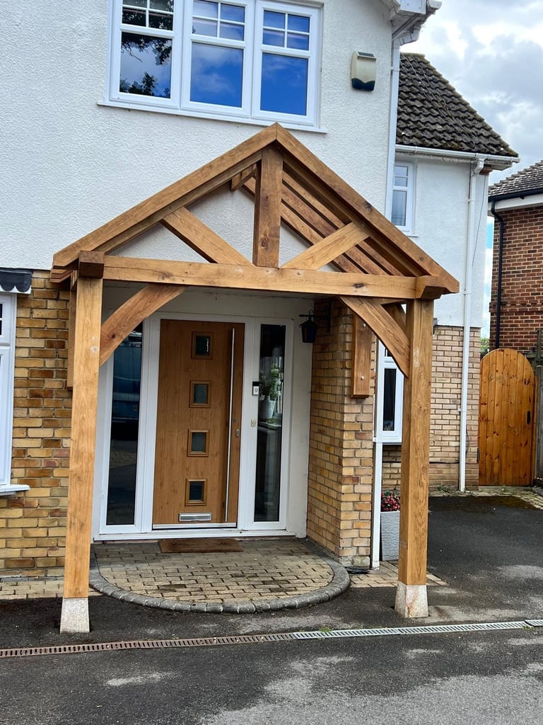 Wooden timber frame porch with gabled roof attached to a brick house with wooden front door